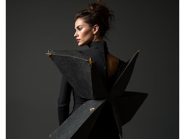 Modèle dans un ensemble avant-gardiste aux formes géométriques et couleurs vives, capturé avec un éclairage dramatique.